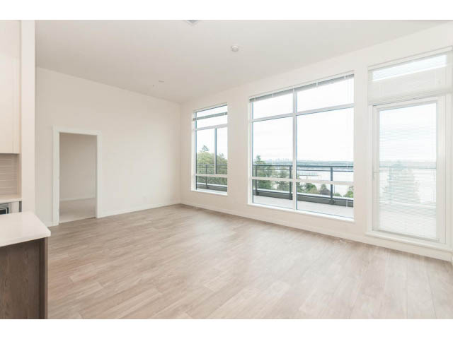 Bright open-concept living space with hardwood floors and large windows offering a city view. - 402 - 625 East 3rd Street, North Vancouver