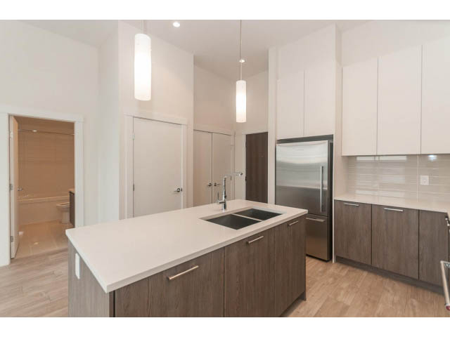 Bright kitchen with white countertops, hardwood floors, and stainless steel appliances. - 402 - 625 East 3rd Street, North Vancouver