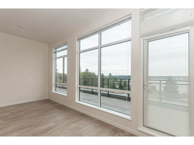 Bright living room with hardwood floors and large windows offering a city view. - 402 - 625 East 3rd Street, North Vancouver