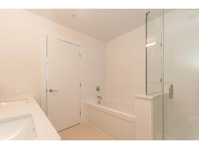 Bright bathroom with white fixtures and glass shower door. - 402 - 625 East 3rd Street, North Vancouver