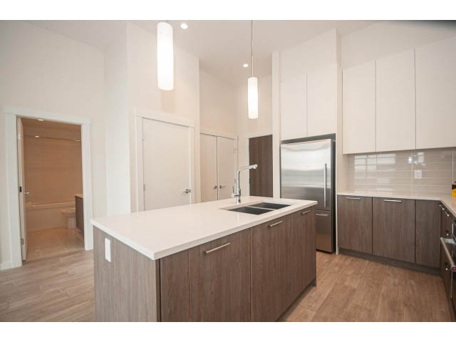Bright kitchen with white cabinets, hardwood floors, and a modern island. - 402 - 625 East 3rd Street, North Vancouver