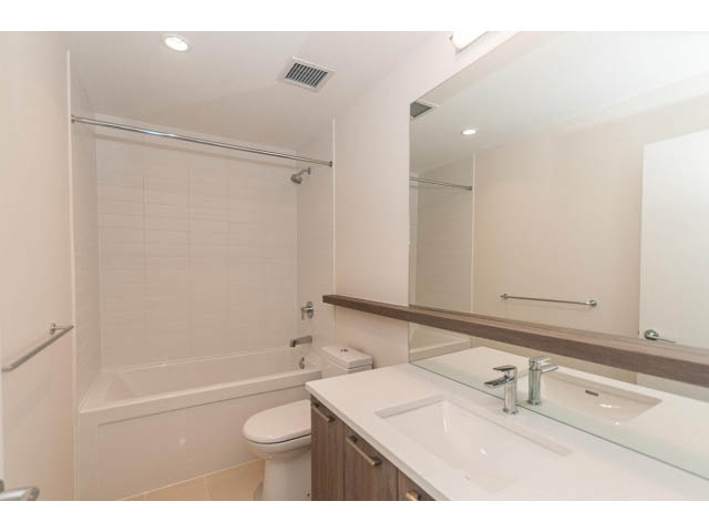 Furnished bathroom with modern sink, large mirror, and shower/tub combo. - 402 - 625 East 3rd Street, North Vancouver