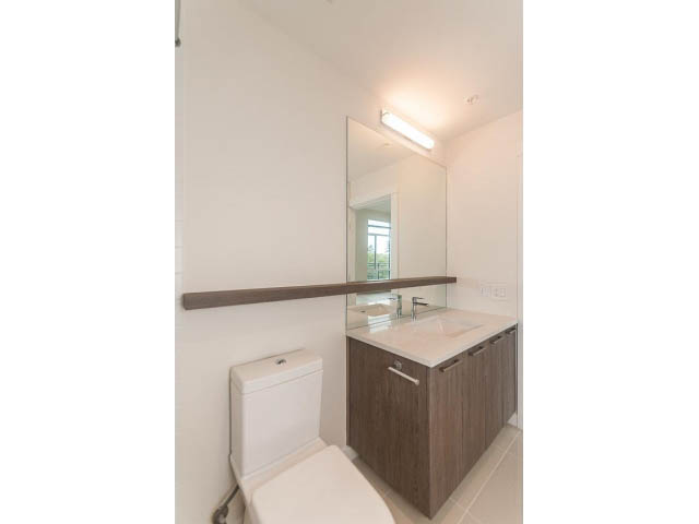 Bright bathroom with modern vanity, large mirror, and city view. - 402 - 625 East 3rd Street, North Vancouver