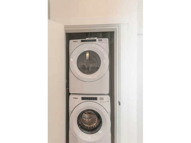 Bright laundry room with stacked washer and dryer, modern design. - 402 - 625 East 3rd Street, North Vancouver
