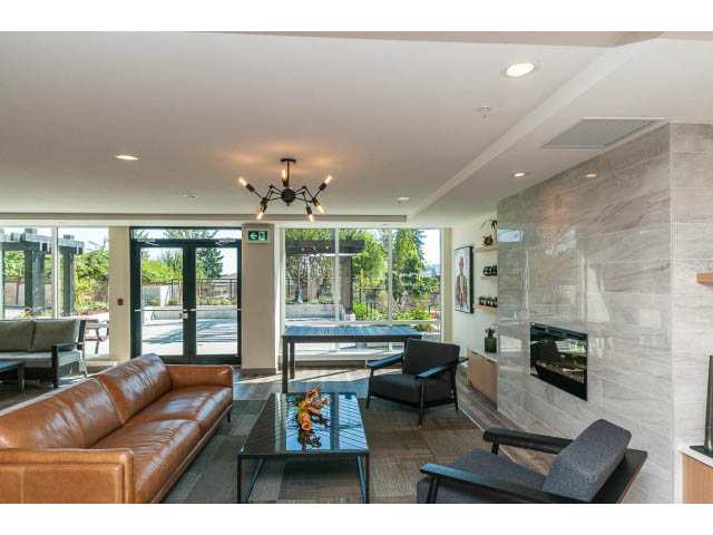 Spacious living room with modern furnishings and large windows, showcasing a city view. - 402 - 625 East 3rd Street, North Vancouver