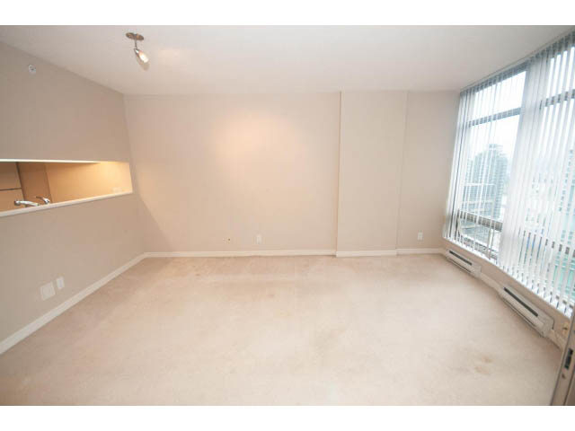 Bright living room with beige carpet, wall-mounted light fixture, and large window with blinds. - 1506 - 1200 Alberni Street, Vancouver Downtown