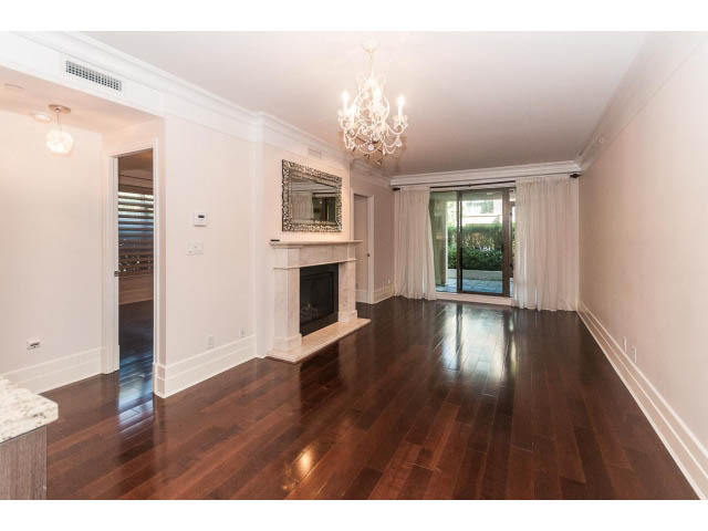 Bright living room with hardwood floors, fireplace, and chandelier. - 104 - 533  Waters Edge Cres, West Vancouver