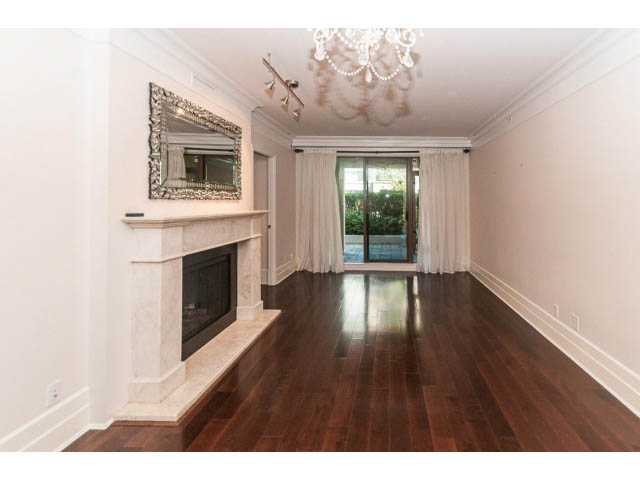 Spacious living room with hardwood floors, fireplace, and chandelier. - 104 - 533  Waters Edge Cres, West Vancouver