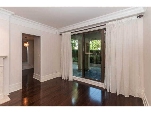 Bright living room with hardwood floors and large sliding glass doors leading to a garden. - 104 - 533  Waters Edge Cres, West Vancouver