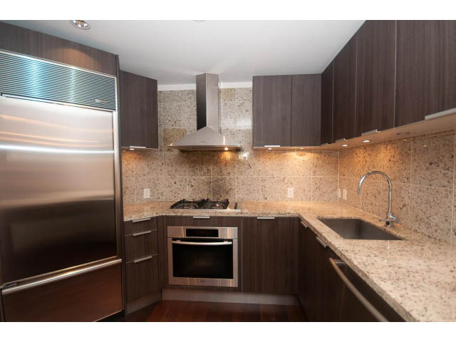 Bright kitchen with granite countertops, stainless steel appliances, and dark wood cabinets. - 104 - 533  Waters Edge Cres, West Vancouver