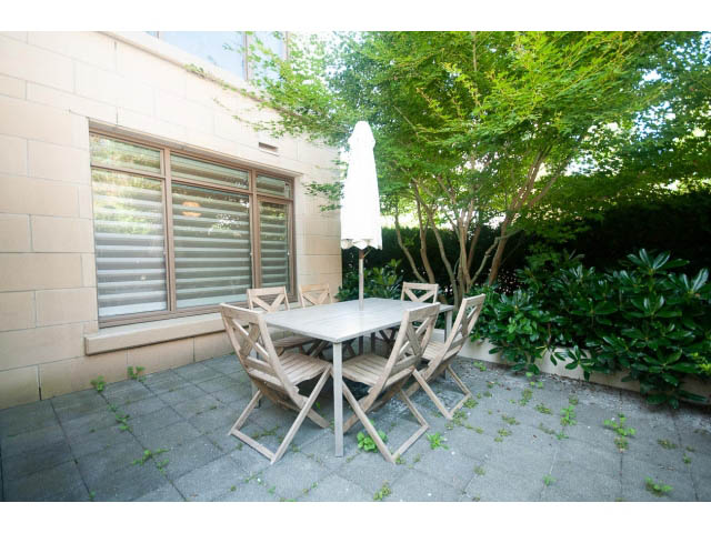 Furnished patio with wooden table and chairs, greenery surrounding. - 104 - 533  Waters Edge Cres, West Vancouver