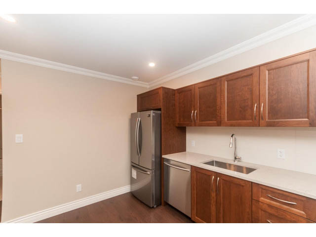 Bright kitchen with wooden cabinets, stainless steel appliances, and hardwood floors. - Suite - 430 West Windsor Road, North Vancouver
