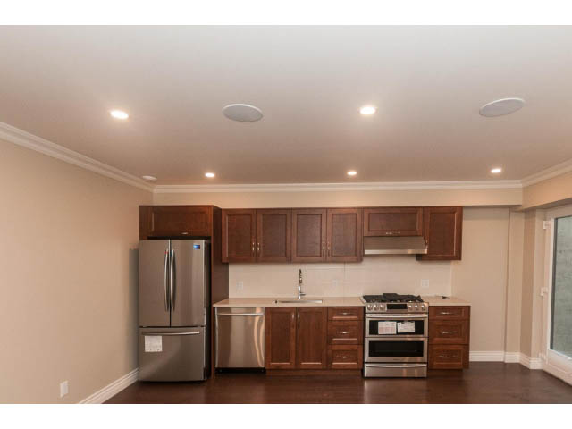 Bright kitchen with wooden cabinets, stainless steel appliances, and hardwood floors. - Suite - 430 West Windsor Road, North Vancouver