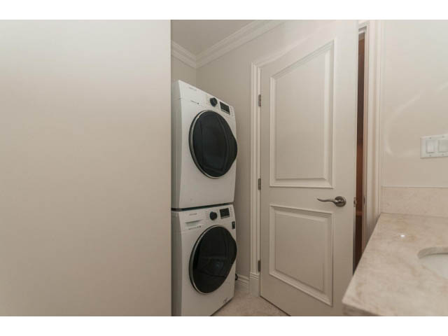 Laundry room with stacked washer and dryer, white cabinets, marble countertop. - Suite - 430 West Windsor Road, North Vancouver