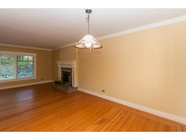 Spacious living room with hardwood floors and a hanging light fixture. - 989 Forest Hills Drive, North Vancouver