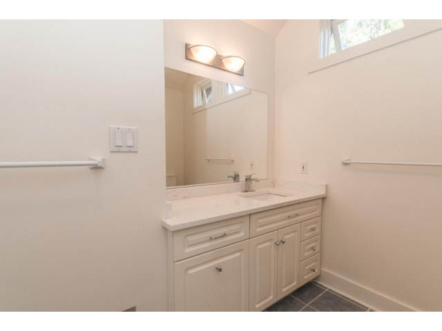 Bright bathroom with white cabinets, countertop, and wall-mounted lights. - 989 Forest Hills Drive, North Vancouver