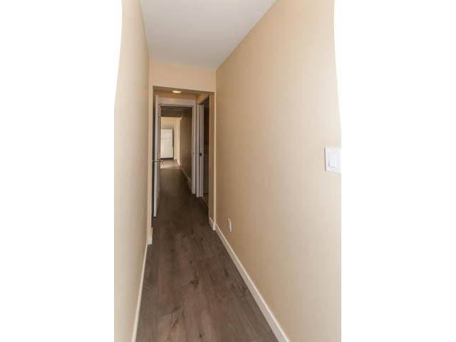 Bright hallway with hardwood floors and light switch visible. - 989 Forest Hills Drive, North Vancouver