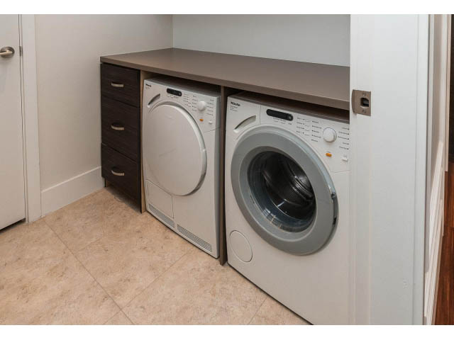 Bright laundry room with modern washer and dryer, dark wood cabinets, and tiled flooring. - 1602 - 667 Howe Street, Vancouver Downtown