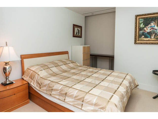 Spacious bedroom with wooden bed, checkered bedding, and bedside lamp. - 1602 - 667 Howe Street, Vancouver Downtown