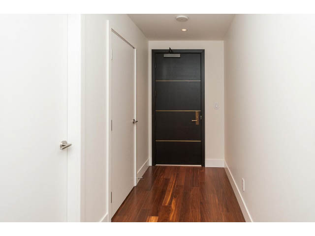 Bright hallway with dark wood flooring and white walls leading to a black door. - 1602 - 667 Howe Street, Vancouver Downtown