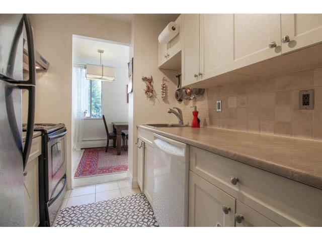 Bright kitchen with white cabinets, granite countertops, and a tiled backsplash. - 309 - 2008 Fullerton Avenue, North Vancouver