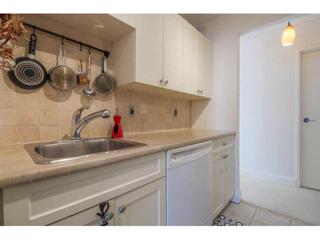 Bright kitchen with white cabinets, granite countertops, and a tiled backsplash. - 309 - 2008 Fullerton Avenue, North Vancouver