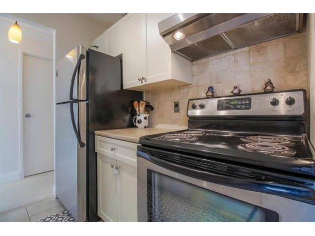 Bright kitchen with white cabinets, stainless steel appliances, and a tiled backsplash. - 309 - 2008 Fullerton Avenue, North Vancouver