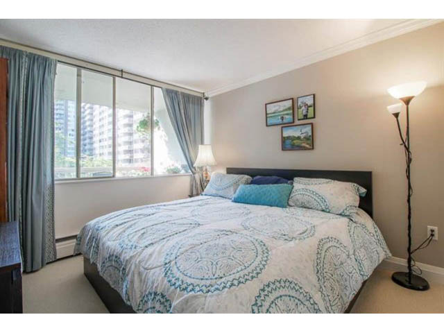 Bright bedroom with large windows, city view, and neatly made bed with blue and white bedding. - 309 - 2008 Fullerton Avenue, North Vancouver