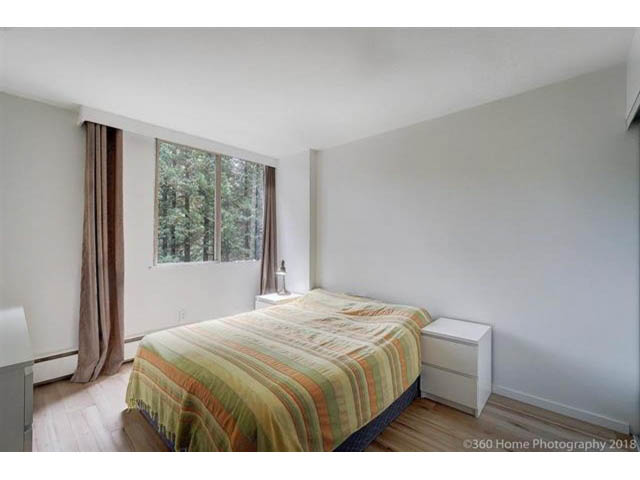 Bright bedroom with hardwood floors, large window, and neatly made bed. - 302 - 2012 Fullerton Avenue, North Vancouver