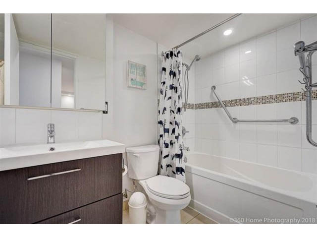 Bright bathroom with white tiles, modern sink, and bathtub with shower curtain. - 302 - 2012 Fullerton Avenue, North Vancouver