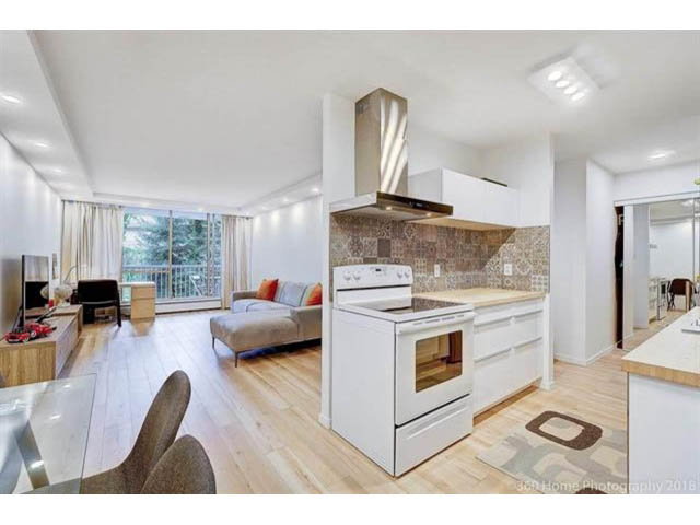 Bright kitchen with white cabinetry, hardwood floors, and a city view. - 302 - 2012 Fullerton Avenue, North Vancouver