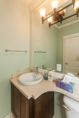 Furnished bathroom with light green walls, wooden vanity, and modern sink. - 196 W 18th Avenue, Vancouver West Side