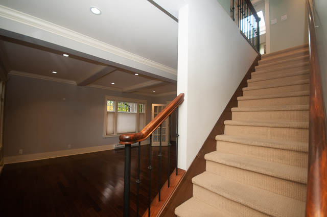 Staircase with wooden banister and carpeted steps leading to upper level. - 196 W 18th Avenue, Vancouver West Side