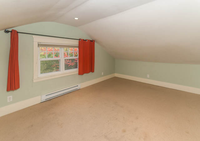 Den with sloped ceiling, red curtains, and a window showing greenery. - 196 W 18th Avenue, Vancouver West Side