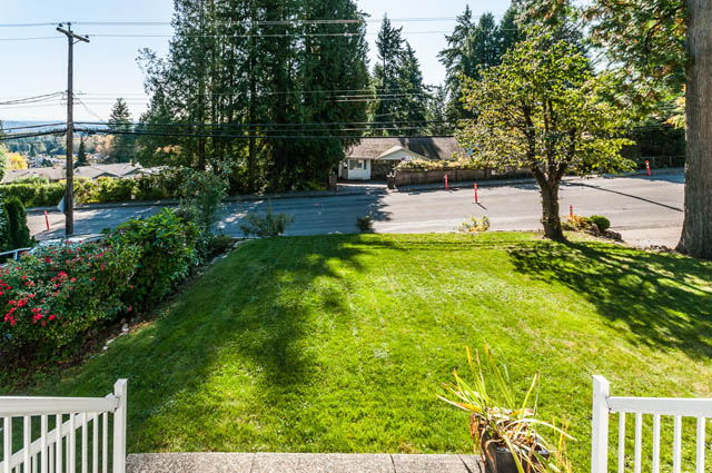 Lush green lawn with a white fence and trees in the background. - UPPER - 630 East 29th Street, North Vancouver