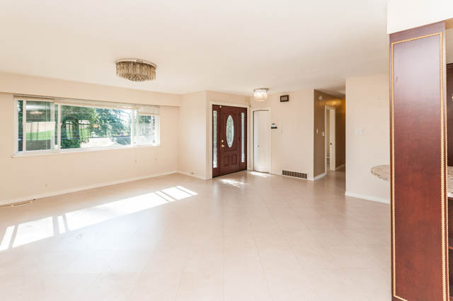 Bright living room with large windows and a chandelier, leading to a hallway. - UPPER - 630 East 29th Street, North Vancouver