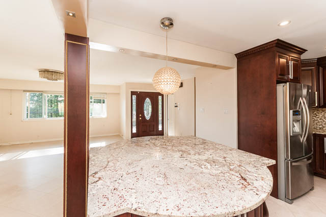 Bright kitchen with granite countertops and wooden cabinets, modern pendant light. - UPPER - 630 East 29th Street, North Vancouver