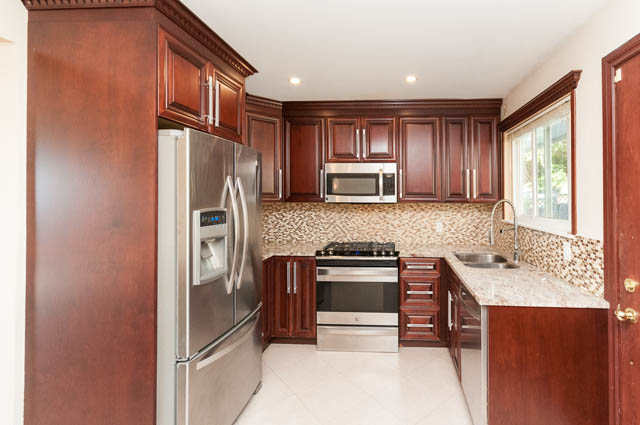 Bright kitchen with dark wood cabinets, granite countertops, and stainless steel appliances. - UPPER - 630 East 29th Street, North Vancouver