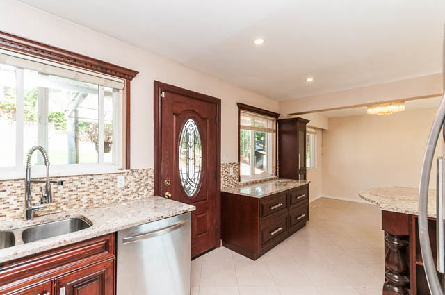 Bright kitchen with granite countertops and dark wood cabinets. - UPPER - 630 East 29th Street, North Vancouver