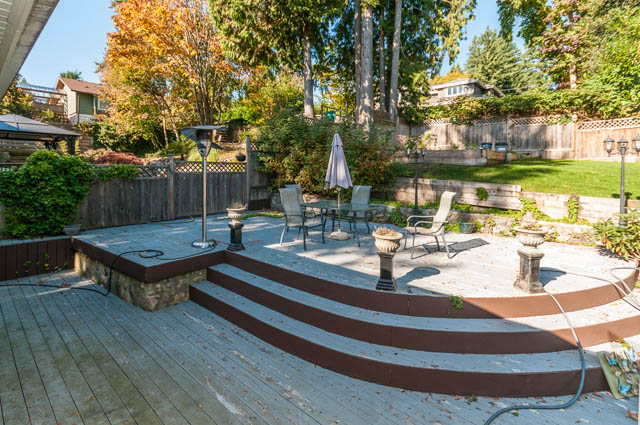 Spacious patio with wooden deck, stone seating, and outdoor furniture. - UPPER - 630 East 29th Street, North Vancouver