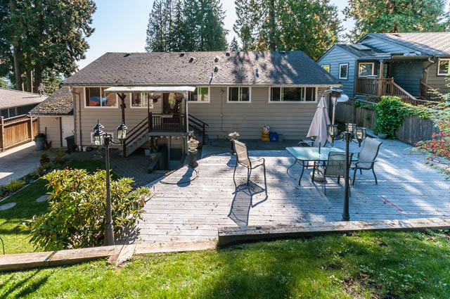 Furnished patio with wooden deck, outdoor furniture, and greenery. - UPPER - 630 East 29th Street, North Vancouver