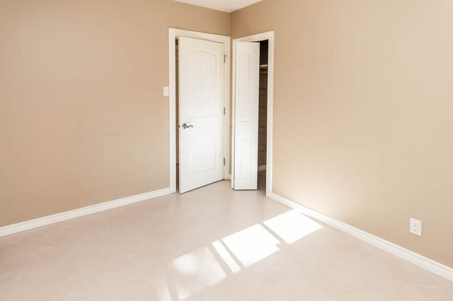 Empty bedroom with beige walls and white trim, door slightly ajar. - UPPER - 630 East 29th Street, North Vancouver