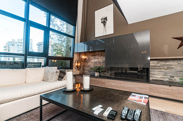 Furnished living room with modern fireplace, city view, and sleek furniture. - PH7 - 1688 Robson Street, Vancouver Downtown