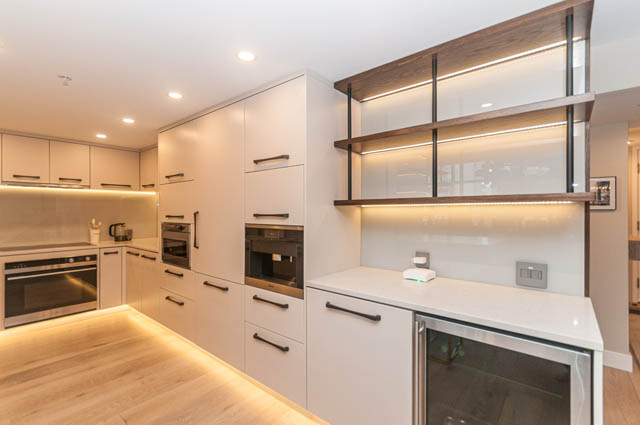 Bright kitchen with modern white cabinetry, hardwood floors, and sleek countertop lighting. - PH7 - 1688 Robson Street, Vancouver Downtown