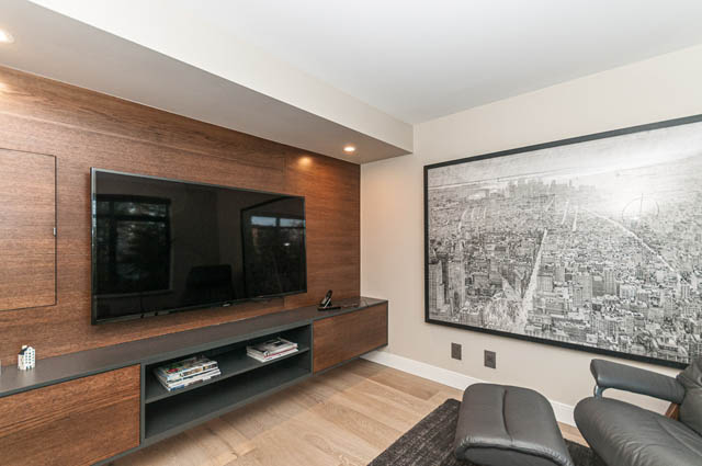 Bright living room with sleek wood paneling, large cityscape mural, and modern furniture. - PH7 - 1688 Robson Street, Vancouver Downtown