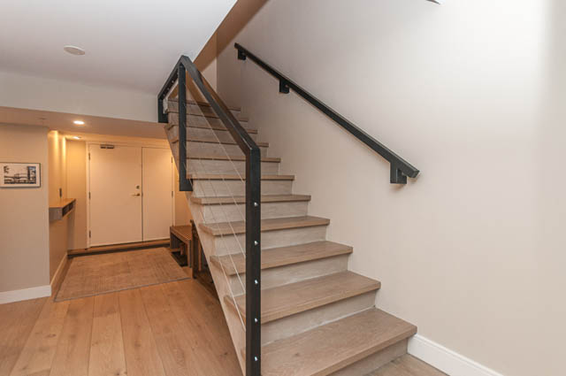 Bright and modern penthouse entryway with hardwood floors and sleek black railings. - PH7 - 1688 Robson Street, Vancouver Downtown