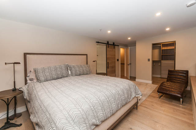 Spacious bedroom with wooden floors, modern furniture, and a sliding door closet. - PH7 - 1688 Robson Street, Vancouver Downtown