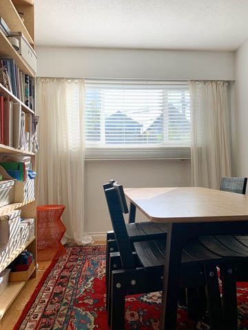 Bright living room with bookshelves, patterned rug, and large windows. - 850 E 23rd Avenue, Vancouver East Side