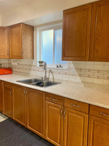 Bright kitchen with light oak cabinets, granite countertops, and a window view. - 850 E 23rd Avenue, Vancouver East Side