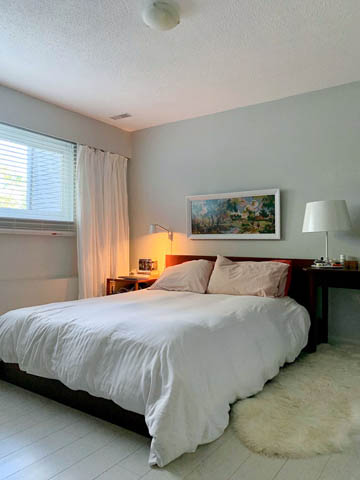 Spacious bedroom with white bedding, hardwood floors, and a fluffy rug. - 850 E 23rd Avenue, Vancouver East Side
